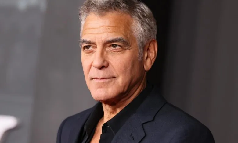 Close-up of George Clooney in a dark suit against a gray backdrop.