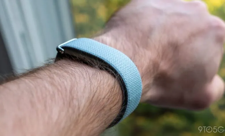 Close-up of a wrist wearing a light blue Fitbit fitness tracker.