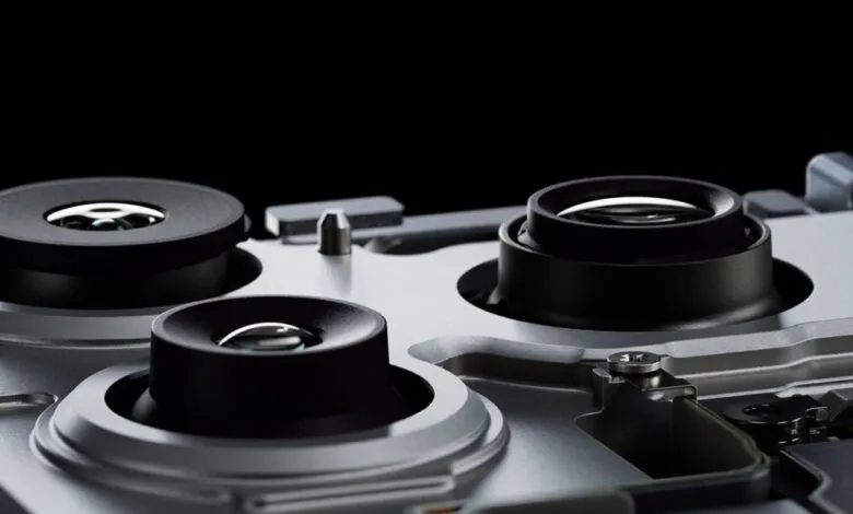 Close-up of three camera lenses on a silver device, black background.