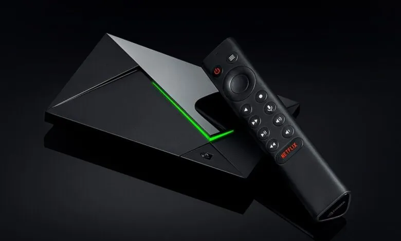 Nvidia Shield TV Pro with remote on a reflective black surface.