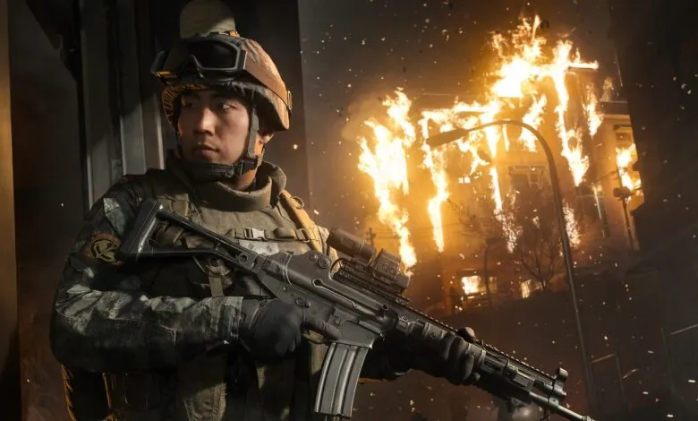 Soldier in combat gear stands guard against a burning building backdrop.