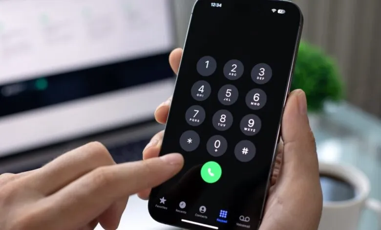 Person dialing a number on a smartphone with keypad displayed.