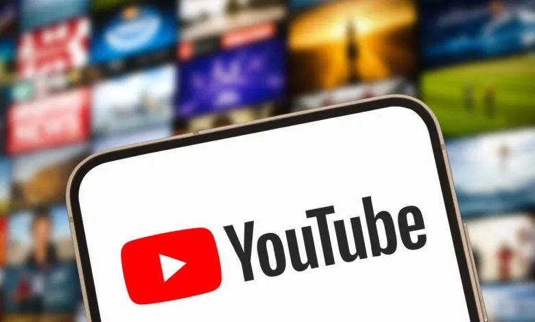 YouTube logo displayed on a smartphone screen with video thumbnails blurred in the background.