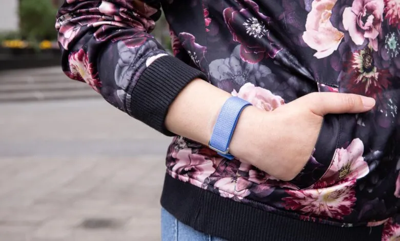 Person wearing a blue woven fitness tracker band with a floral jacket outdoors