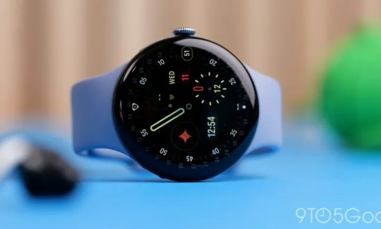 Close-up of a smartwatch with a round black screen and blue band resting on a blue surface.
