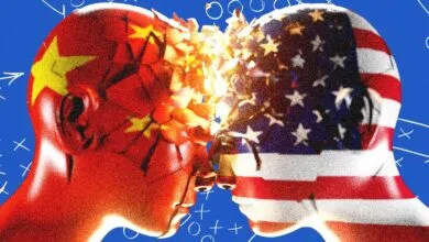 Two human heads stylized with the Chinese and US flags clashing and shattering on a blue background