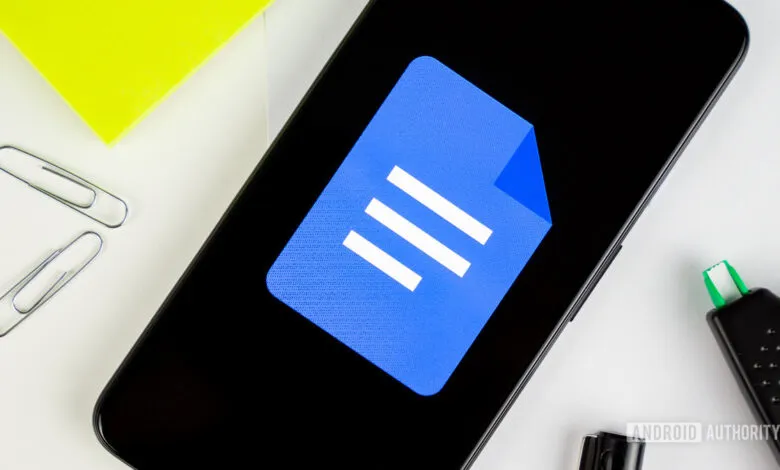 Google Docs logo displayed on a smartphone screen surrounded by office supplies