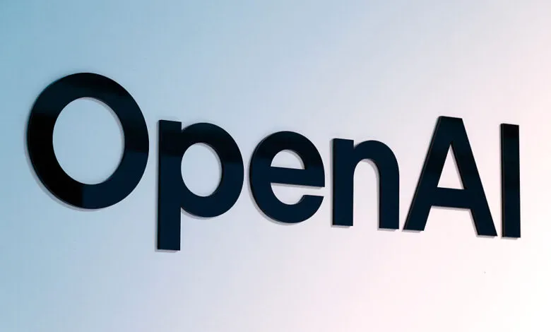 Black OpenAI logo lettering mounted against a white and light blue gradient wall.