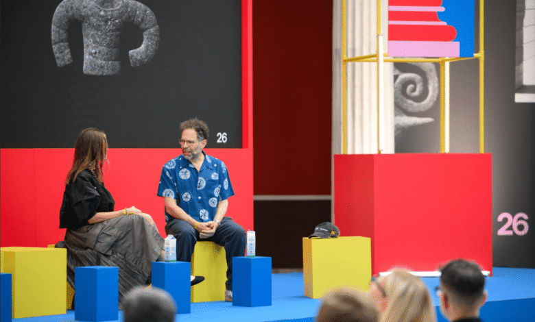 Panel discussion with two people on a vibrant yellow, red, and blue stage.