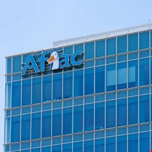 Exterior view of a modern glass office building featuring the blue Aflac logo with its signature duck icon.