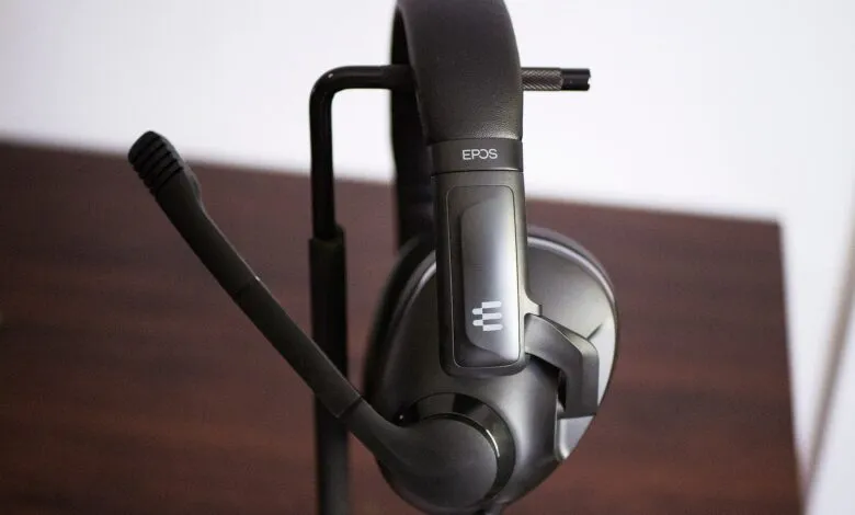 Black EPOS gaming headset hanging neatly on a metal stand against a neutral background.