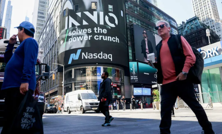 Pedestrians walk past a massive digital billboard displaying INNIO and Nasdaq in Times Square, New York.