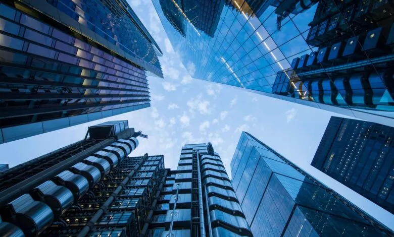 Low angle view looking up at towering modern skyscrapers against a partly cloudy sky.