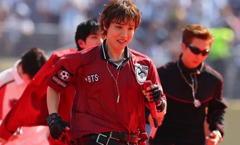 J-Hope of BTS performs on stage in a red jersey holding a red microphone