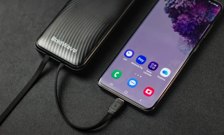 Smartphone connected to a sleek BoldWave power bank via a black USB cable on a dark surface.