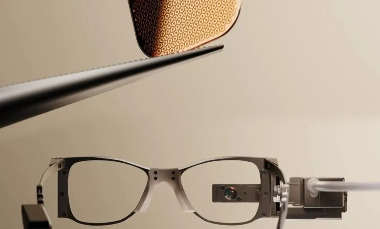 Tweezers hold a tiny microchip above specialized glasses with an embedded camera.