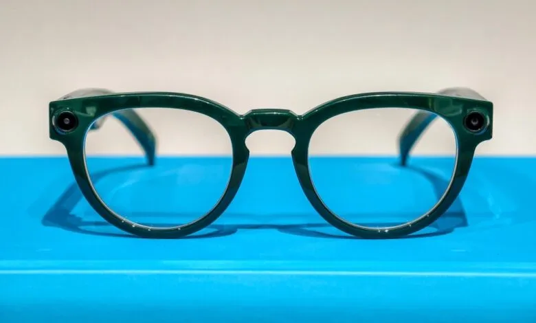 Green smart glasses with built-in cameras resting on a bright blue surface