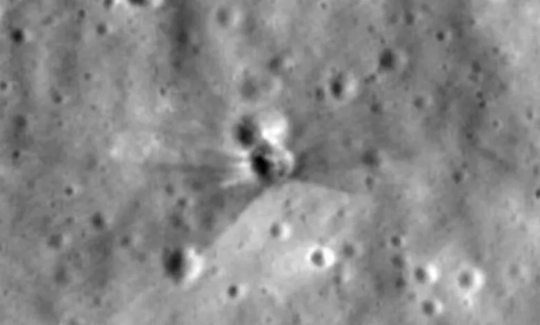 Black and white close-up of a crater on the Moon's surface with ejecta rays