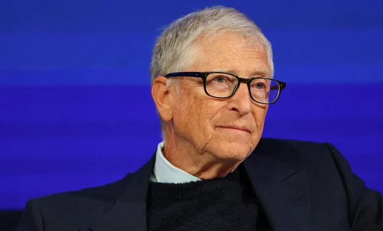 Bill Gates wearing glasses and a dark blazer against a vibrant blue background