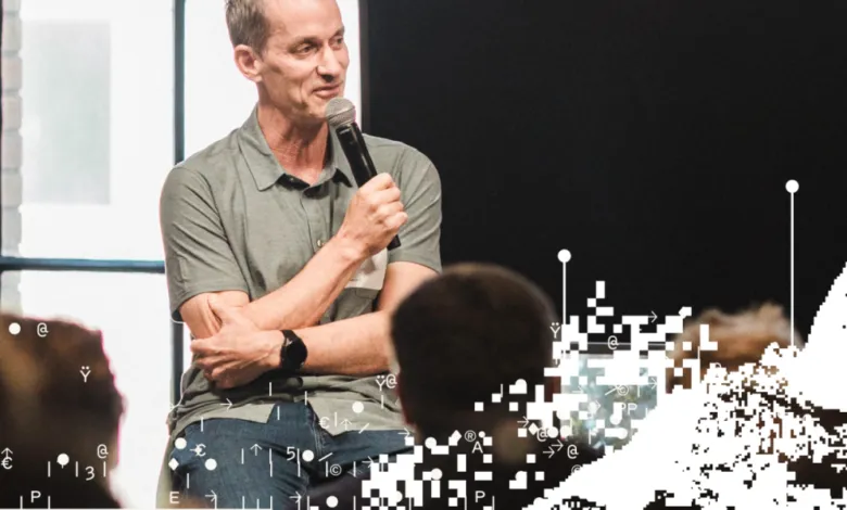 Jeff Dean speaking into a microphone on stage during a tech event