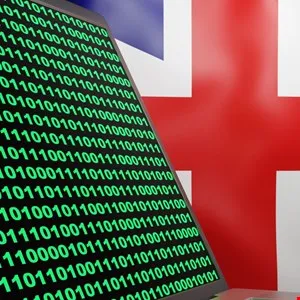 A laptop screen displaying green binary code against a blurred British flag background.