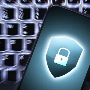 Smartphone screen displaying a glowing security shield and padlock icon over a blurred keyboard background