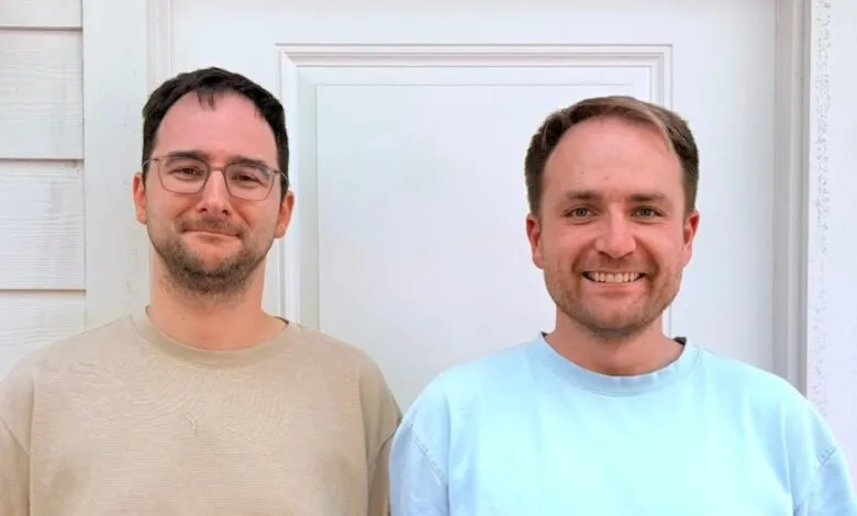 Matthias Petri and Andrey Styskin pose together in front of a white wall.