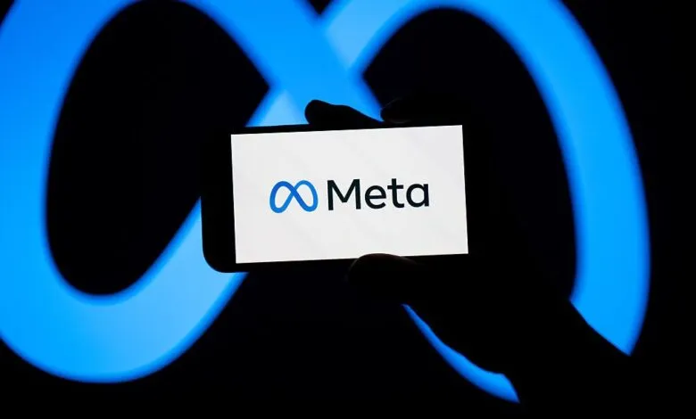 A smartphone displaying the Meta logo against a glowing blue infinity symbol background