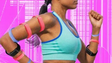 Runner wearing multiple screenless fitness trackers in vibrant pink, blue, and black against a neon background.