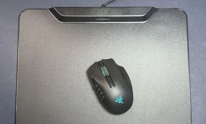 Black Razer gaming mouse resting on a matching metallic Razer hard mousepad on a dark textured desk.