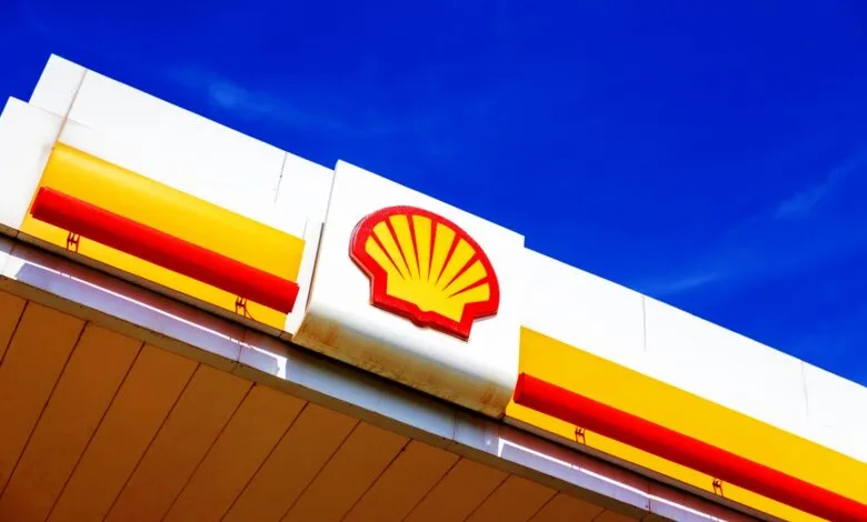 Shell gas station canopy with iconic red and yellow logo against a vibrant blue sky.