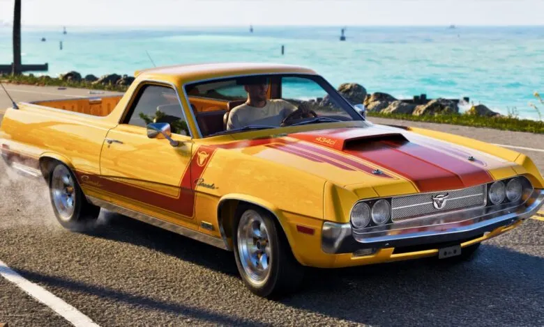 Yellow and red Vapid Ganado retro muscle car driving along a coastal road next to the sea