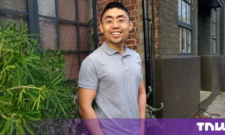 Cliff Tan, known as Dear Modern, smiles outdoors in front of a brick building.