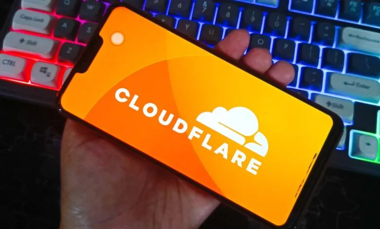 Smartphone displaying Cloudflare app against a glowing mechanical keyboard