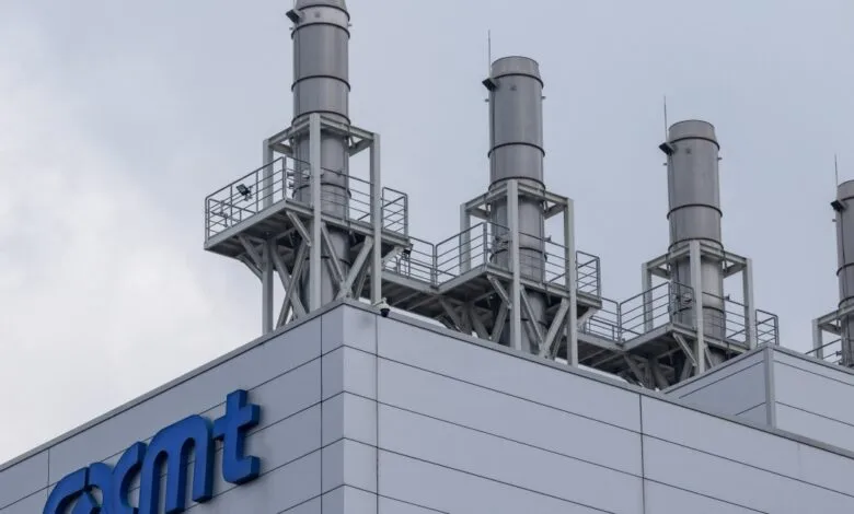 Industrial building roof with four metallic exhaust chimneys against a cloudy sky