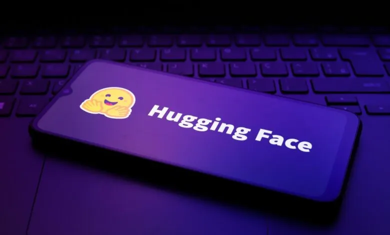 Smartphone displaying the Hugging Face logo resting on a dark backlit laptop keyboard.