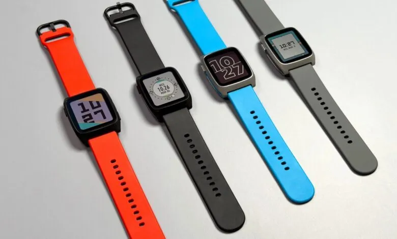 Four smartwatches with colorful straps in red, black, blue, and grey on a light background