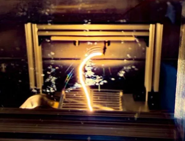 A glowing arc of light inside a mechanical testing machine in a dark laboratory.