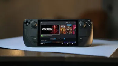 Black Steam Deck handheld gaming console displaying the user interface on a light blue surface