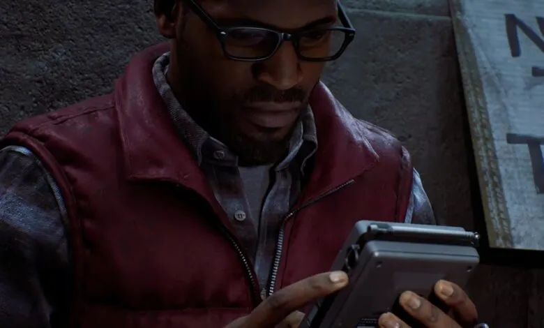 Man wearing glasses and a red vest examining a small electronic device.