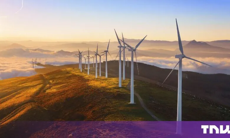 Row of white wind turbines on a misty mountain ridge at sunrise