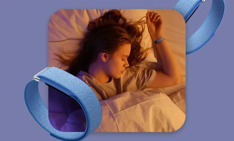 A woman sleeping peacefully while wearing a blue fitness tracker band on her wrist.