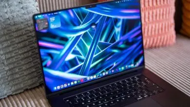 A MacBook Pro displaying a vibrant blue and purple abstract wallpaper with interactive desktop widgets.