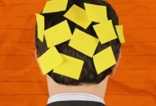 The back of a person's head covered in yellow sticky notes against an orange background.