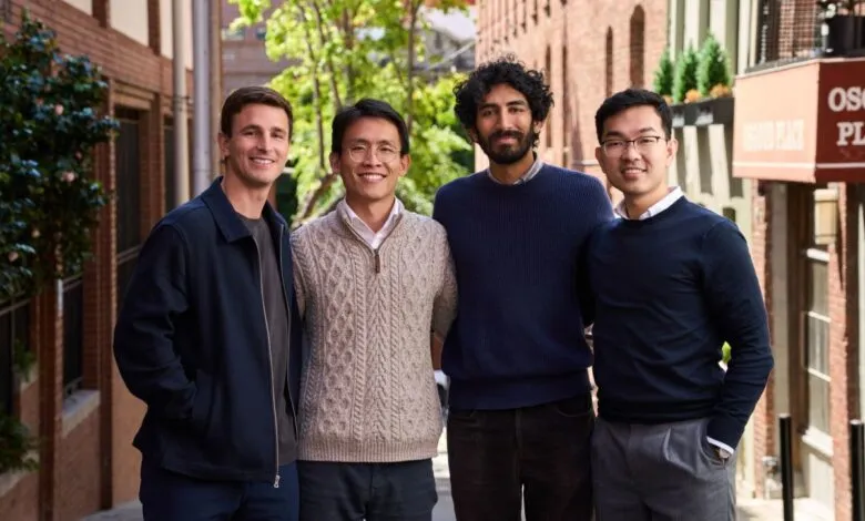 Four young male professionals smiling together outdoors in an urban alleyway.