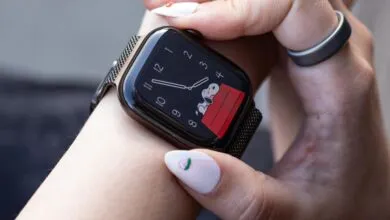 Close-up of a person wearing an Apple Watch with a Snoopy watch face and a dark mesh band.
