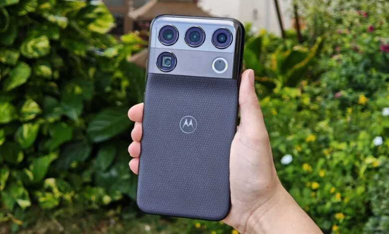 A hand holds a sleek smartphone displaying a textured back and a large multi-lens camera module.
