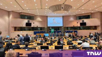 Attendees gather in a large, semi-circular European Parliament hall during a quantum tech conference.