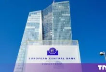 The European Central Bank skyscraper in Frankfurt against a bright blue sky.