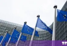 Row of European Union flags waving in front of the Berlaymont building in Brussels.